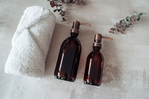 A white bath towel and two bottles of liquid soap