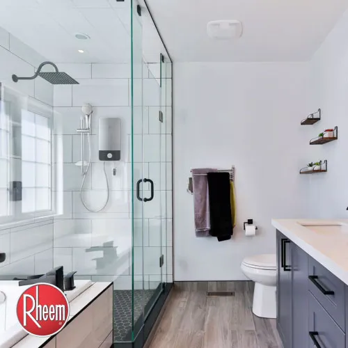 An electric shower heater seen inside minimalist bathroom with glass door