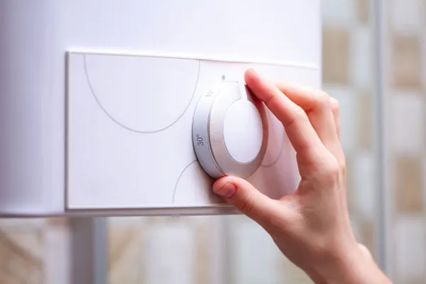 A hand holding temperature knob of water heater